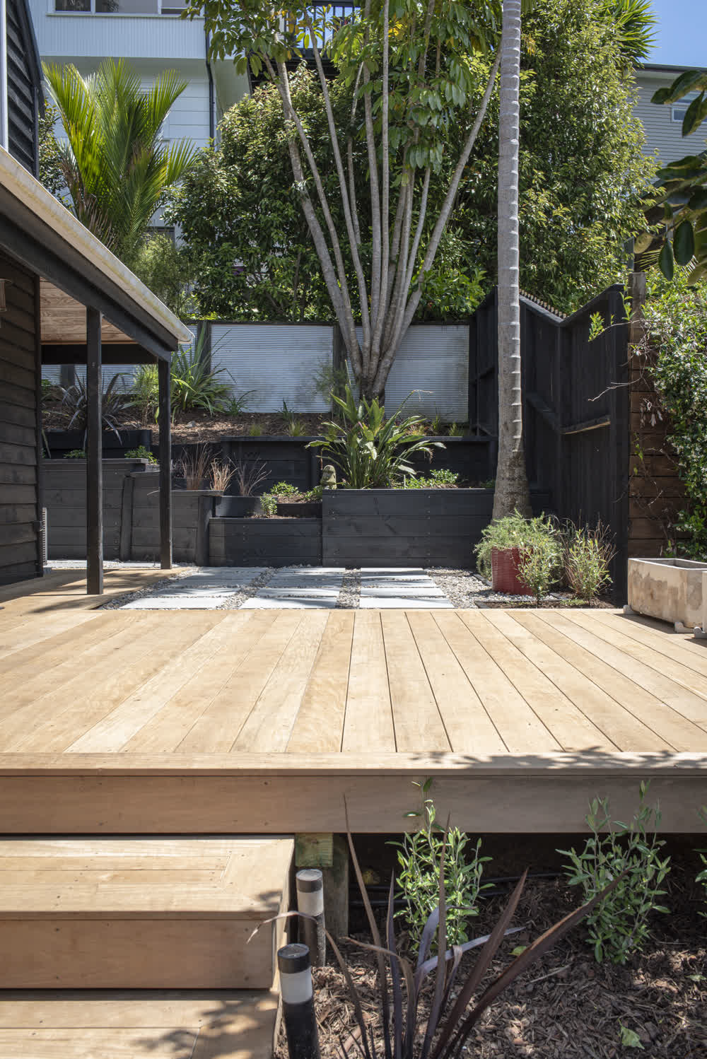 Deck wrapping around house with layered garden and paving